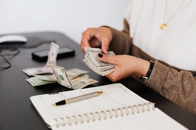 Inicio crop payroll clerk counting money while sitting at table